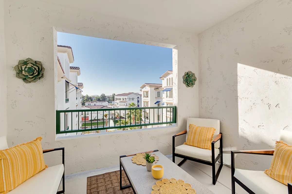 A cheerful interior scene with a cozy seating arrangement beside a large window, decorated with plants and stylish accents. The setting offers inviting views to the outside, suggesting a bright, sun-lit atmosphere ideal for morning coffee or quiet reading moments.