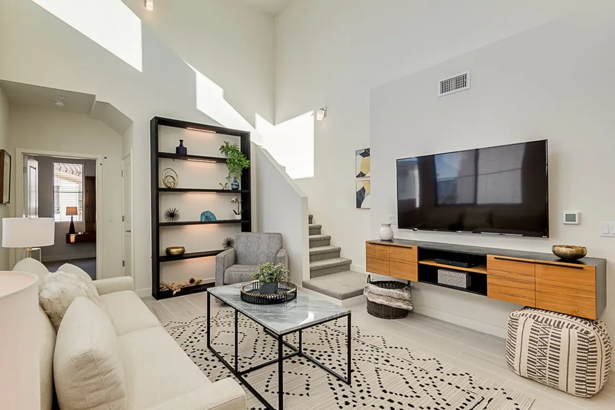 A stylish and comfortable lounge area with a plush sofa, coffee table, TV, and bookshelf. The space is designed for relaxing, watching TV, reading, or socializing, embodying both relaxation and the potential for community interaction within the clubhouse or shared social areas.
