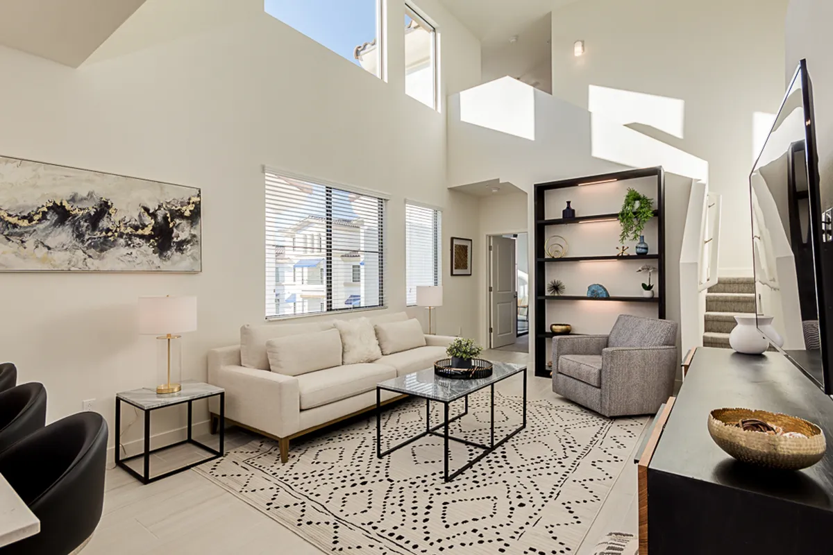 A cozy corner of the living room featuring a plush sofa, stylish coffee table, striking wall artwork, and a bookshelf. Expansive windows allow natural light to fill the space, providing tranquil views and an inviting atmosphere for relaxation or socializing.