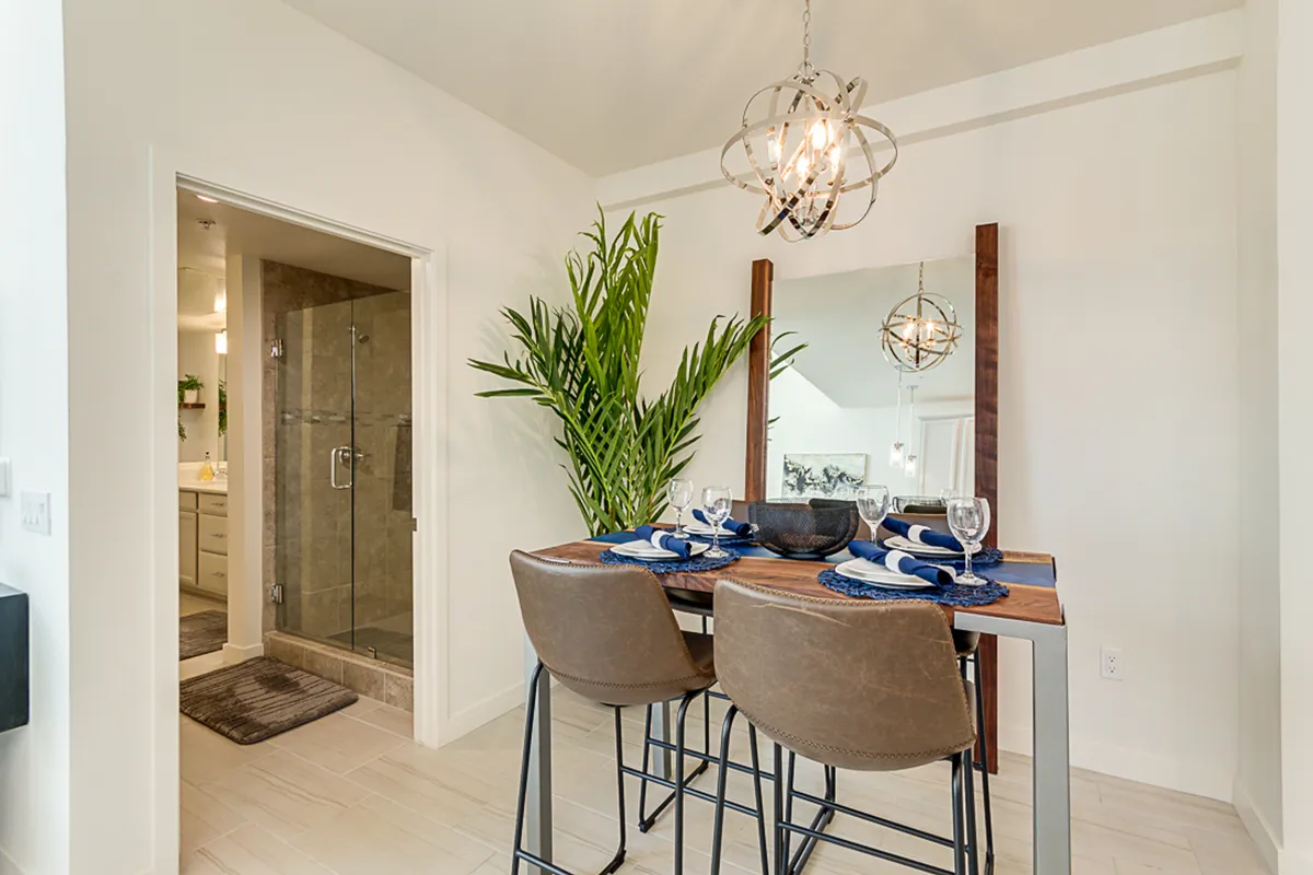 A modern dining space with a large mirror, decorative plant, and statement chandelier, set for dining and entertaining. The room is bright, inviting, and well-suited for casual brunches, dinners, and social gatherings.
